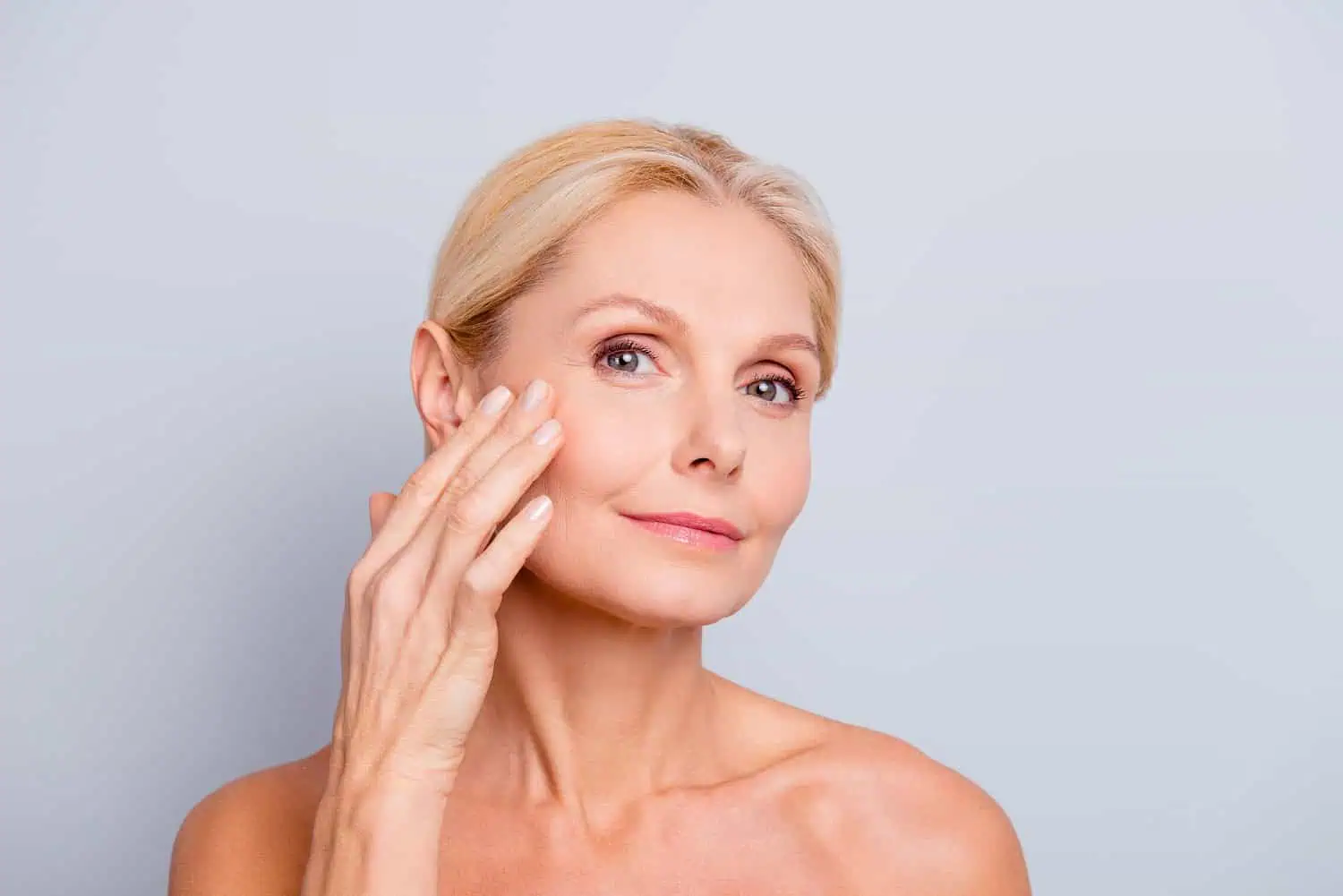 Old woman touching her face after getting Sculptra Biostimulators in Beverly Hills, CA | Maven Medispa